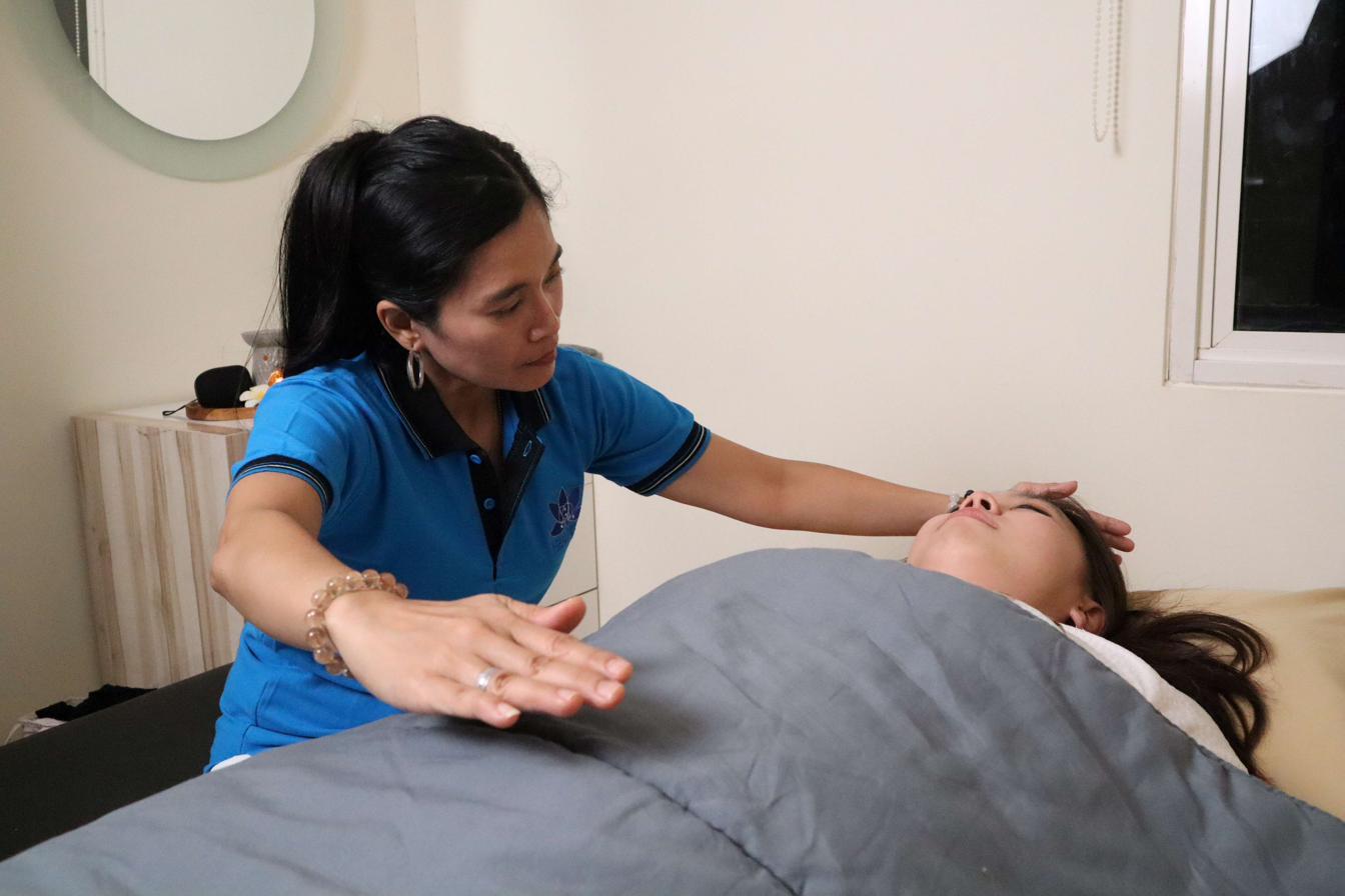 Healer melakukan sapuan energi di atas klien yang berbaring