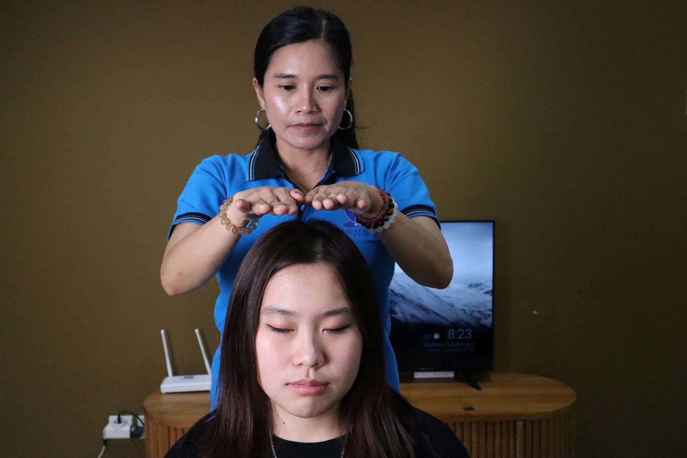 Healer Healingku melakukan sapuan energi reiki di area wajah klien
